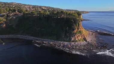 Güneş batarken Palos Verdes 'in nefes kesen sahili, okyanusun üzerindeki engebeli kayalıkları ve evleri aydınlatan hava çekimi Palos Verdes Emlak, Kaliforniya