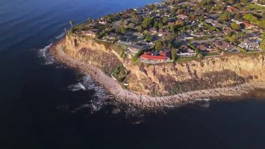 Güneş batarken Palos Verdes 'in nefes kesen sahili, okyanusun üzerindeki engebeli kayalıkları ve evleri aydınlatan, Palos Verdes Evleri, Kaliforniya