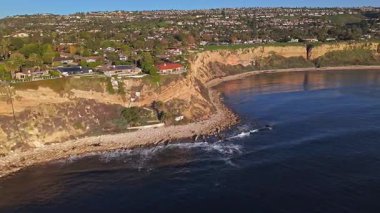 Güneş batarken, okyanusun üzerindeki engebeli kayalıkları ve evleri aydınlatan, nefes kesici Lunada Körfezi çekimleri Palos Verdes Evleri, Kaliforniya