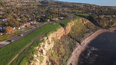 Güneş batarken, okyanusun üzerindeki engebeli kayalıkları ve evleri aydınlatan, nefes kesici Lunada Körfezi 'nin yüksek hava sarmalı görüntüsü, Palos Verdes Emlak, Kaliforniya