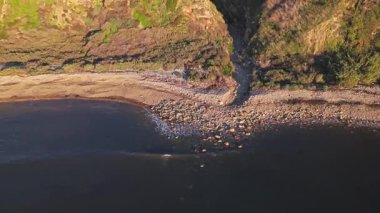 Güneş batarken nefes kesen Lunada Körfezi 'nin hava aracı görüntüsü okyanusun üzerindeki engebeli kayalıkları ve evleri aydınlatıyor, Palos Verdes Evleri, Kaliforniya
