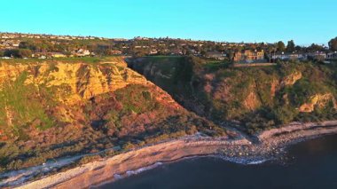 Güneş batarken, okyanusun üzerindeki engebeli kayalıkları ve evleri aydınlatan, nefes kesici Lunada Körfezi Kanyonu 'nun hava yörüngesi çekimi, Palos Verdes Emlak, Kaliforniya