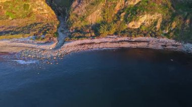 Hava yörüngesinde güneş batarken nefes kesen Lunada Körfezi Kanyonu 'nun okyanusun üzerindeki engebeli kayalıkları ve evleri aydınlattığı görülüyor. Palos Verdes Evleri, Kaliforniya