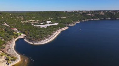 Güneşli bir sonbahar gününde, Travis Gölü 'nün yüksek hava akıntısı engebeli kayalıkları ve çarpıcı göl evleri Austin, Teksas