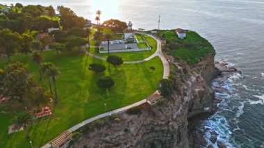 Los Angeles, Kaliforniya 'daki Point Fermin Deniz Feneri' nin hava yörüngesi görüntüsü. Renkli gökyüzü, engebeli uçurumlar ve kıyı boyunca dalgalar çarpıyor.