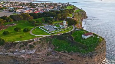 Los Angeles, Kaliforniya 'daki Point Fermin Deniz Feneri' nin hava yörüngesi görüntüsü. Renkli gökyüzü, engebeli uçurumlar ve kıyı boyunca dalgalar çarpıyor.