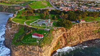 Los Angeles, Kaliforniya 'daki Point Fermin Deniz Feneri' nin hava yörüngesi görüntüsü. Renkli gökyüzü, engebeli uçurumlar ve kıyı boyunca dalgalar çarpıyor.