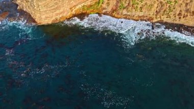 Los Angeles, Kaliforniya 'daki Point Fermin Deniz Feneri' nin sinematik hava yörüngesinde altın saatinde renkli gökyüzü, engebeli uçurumlar ve kıyı boyunca dalgaların çarpıştığı görülüyor.