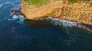 Los Angeles, Kaliforniya 'daki Point Fermin Deniz Feneri' nin hava yörüngesinde altın saatinde renkli gökyüzü, engebeli uçurumlar ve kıyıya vuran dalgalar görülüyor.