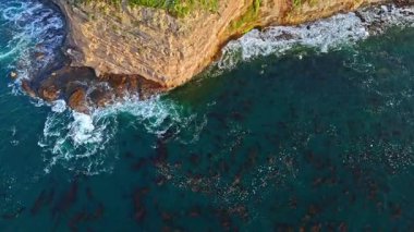 Los Angeles, Kaliforniya 'daki Point Fermin Deniz Feneri' nin en tepeden aşağı görüntüsü. Renkli gökyüzü, engebeli uçurumlar ve sahil boyunca dalgalar çarpışıyor.