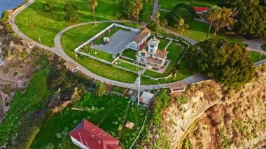 Los Angeles, Kaliforniya 'daki Point Fermin Deniz Feneri' nin havadan çekilmiş görüntüleri. Renkli gökyüzü, engebeli uçurumlar ve sahil boyunca dalgalar çarpışıyor.