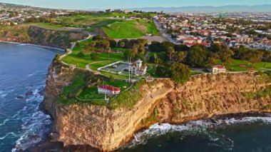 Los Angeles, Kaliforniya 'daki Point Fermin Deniz Feneri' nin alçak hava sarmal görüntüsü. Renkli gökyüzü, engebeli uçurumlar ve kıyıya vuran dalgalar.
