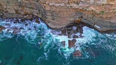 Los Angeles, Kaliforniya 'daki Point Fermin uçurumlarının en tepedeki yükselen hava aracı görüntüleri. Renkli gökyüzü, engebeli uçurumlar ve sahil boyunca dalgalar çarpışıyor.