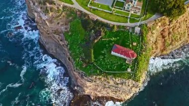 Los Angeles, Kaliforniya 'daki Point Fermin uçurumlarının en yüksek yörüngesinde. Renkli gökyüzü, engebeli uçurumlar ve kıyı boyunca dalgalar çarpışıyor.