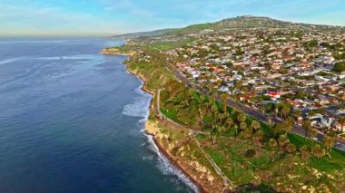 Engebeli uçurumların üzerinde güzel evler ve kıyı boyunca dalgaların çarptığı engebeli San Pedro, Kaliforniya kıyılarının yüksek hava akıntısı.