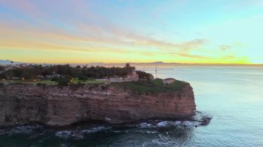 Point Fermin 'in Los Angeles, Kaliforniya' daki mavi saat görüntülerine hava saldırısı. Renkli gökyüzü, engebeli uçurumlar ve kıyı boyunca dalgalar çarpışıyor.