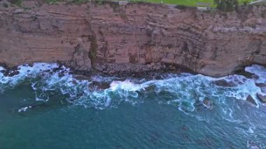 Los Angeles, Kaliforniya 'daki Point Fermin Deniz Feneri' nin renkli gökyüzü, engebeli uçurumlar ve kıyıya vuran dalgalarla gündoğumundan hemen önce çekilmiş görüntüsü.