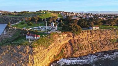 Los Angeles, Kaliforniya 'daki Point Fermin Deniz Feneri' nin alçak hava yörünge görüntüsü. Renkli gökyüzü, engebeli uçurumlar ve kıyıya vuran dalgalar.