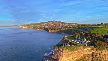 Los Angeles, Kaliforniya 'daki Point Fermin Deniz Feneri' nin yüksek hava akımı. Renkli gökyüzü, engebeli uçurumlar ve kıyıya vuran dalgalar.