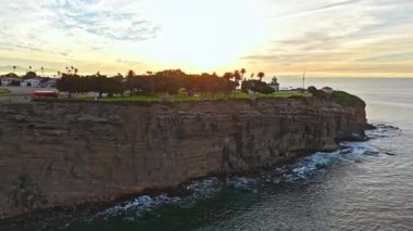 Los Angeles, Kaliforniya 'daki Point Fermin Deniz Feneri' nin renkli gökyüzü, engebeli uçurumlar ve kıyıya vuran dalgalarla altın saatinde çekilmiş hava sarmalı görüntüleri.