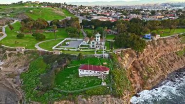 Los Angeles, Kaliforniya 'daki Point Fermin Deniz Feneri' nin alçak hava sarmal görüntüsü. Renkli gökyüzü, engebeli uçurumlar ve kıyıya vuran dalgalar.
