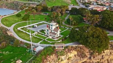 Los Angeles, Kaliforniya 'daki Point Fermin Deniz Feneri' nin alçak hava sarmal görüntüsü. Renkli gökyüzü, engebeli uçurumlar ve kıyıya vuran dalgalar.