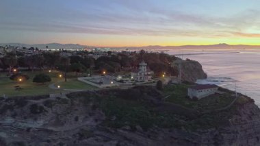 Point Fermin 'in mavi saatinde Los Angeles, Kaliforniya' daki hava yörüngesi görüntüsü. Renkli gökyüzü, engebeli uçurumlar ve kıyı boyunca dalgalar çarpışıyor.