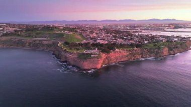 Point Fermin 'in Los Angeles, Kaliforniya' daki yüksek hava yörüngesi görüntüsü. Mavi saat, gökyüzü, engebeli uçurumlar ve kıyı boyunca dalgalar çarpışıyor.