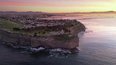 Point Fermin 'in Los Angeles, Kaliforniya' daki yüksek hava yörüngesi görüntüsü. Mavi saat, gökyüzü, engebeli uçurumlar ve kıyı boyunca dalgalar çarpışıyor.