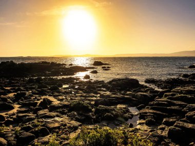 Gün batımında Arousa adasındaki kayalar