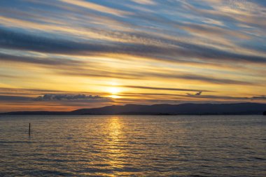 Arousa nehri Vilagarcia de Arousa 'dan altın ve bulutlu gün batımında