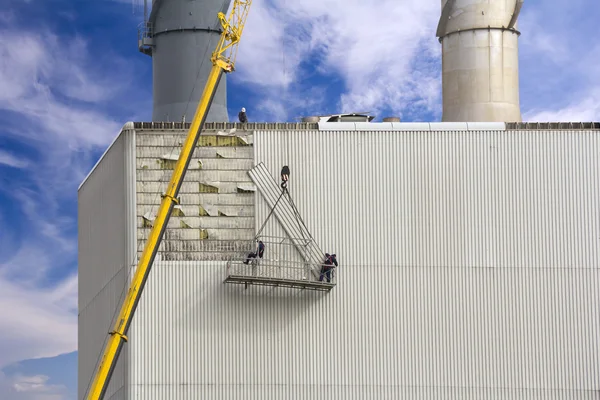 Trabajadores colgando de la grúa y reparando paneles de pared en calor — Foto de Stock