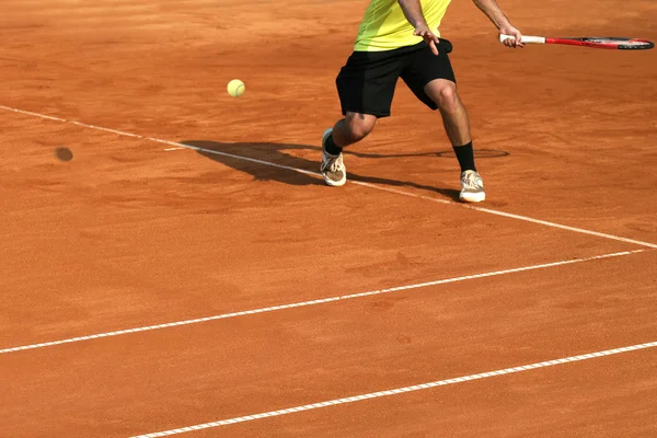 Jogador de tênis masculino em ação na quadra em um dia ensolarado — Fotografia de Stock