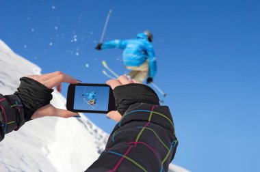 Photographed skiers jump with cell phone clipart