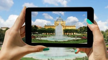 Bir cep telefonu kullanarak genç kız turist kayıtları çeşme ve sanat Zagreb'de köşk