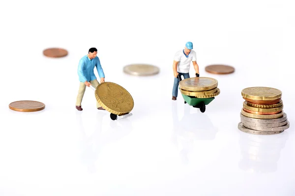 Два миниатюрных работника управляют монетами евро — стоковое фото