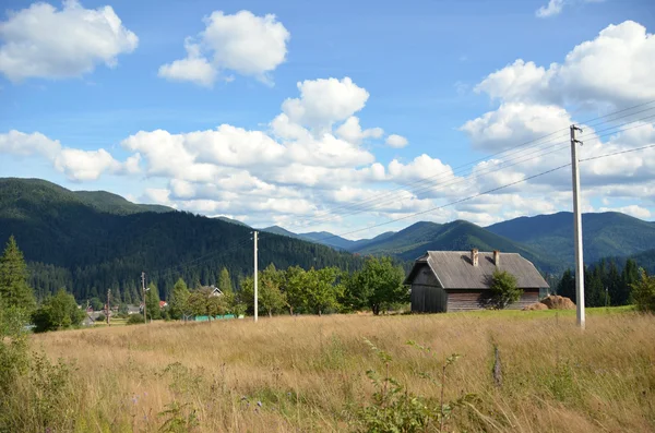 Blick auf ein kleines Haus auf einem Hintergrund von Bergen und blauem Himmel — Stockfoto