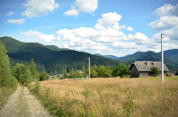 Fußweg mit einem Haus auf einem Hintergrund von Bergen und blauem Himmel — Stockfoto