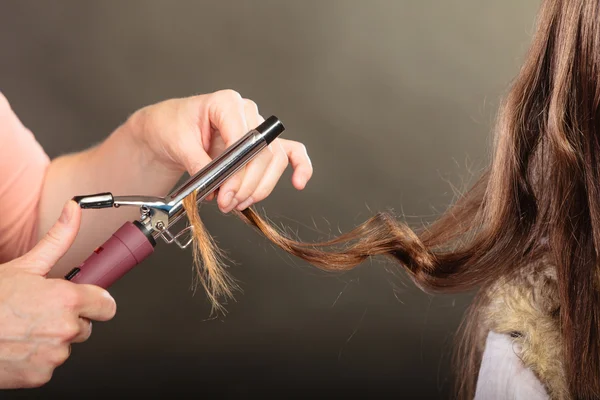 Styliste cheveux de curling pour jeune femme. — Photo