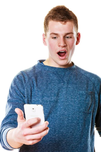 Удивленный молодой человек смотрит на мобильный телефон — стоковое фото