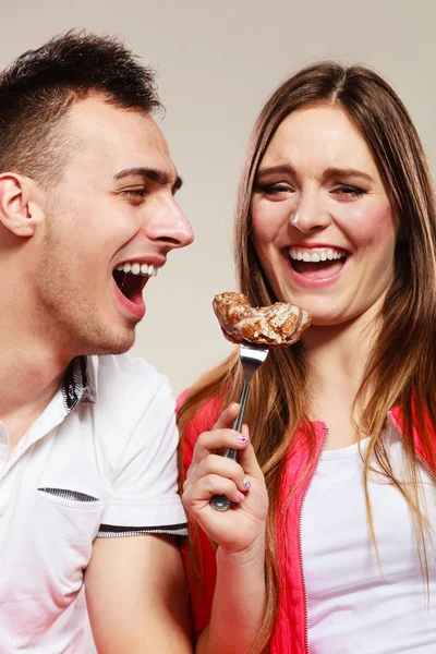 Uśmiechnięta kobieta karmi szczęśliwego mężczyznę ciastem. — Zdjęcie stockowe
