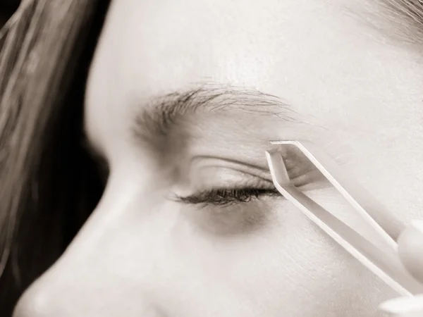 Woman tweezing eyebrows depilating with tweezers — Stock Photo, Image