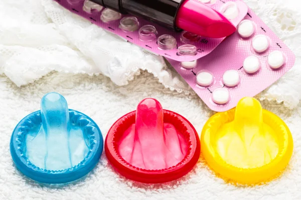 Pills condoms and lipstick on lace lingerie — Stock Photo, Image