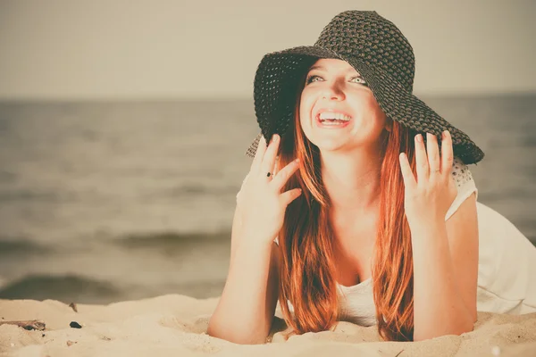 Vacker rödhårig glad flicka i svart hatt på stranden. — Stockfoto