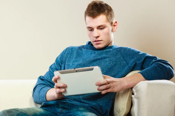 Giovane con tablet seduto sul divano a casa — Foto Stock