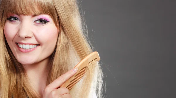 Mujer de cerca peinándose el pelo con peine — Foto de Stock