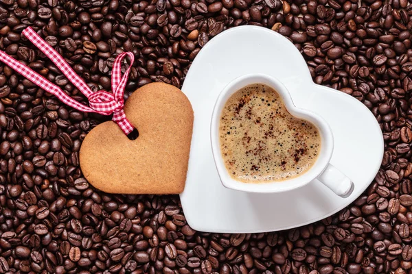 Heart shaped cup and cookie on coffee beans background — Stock Photo, Image