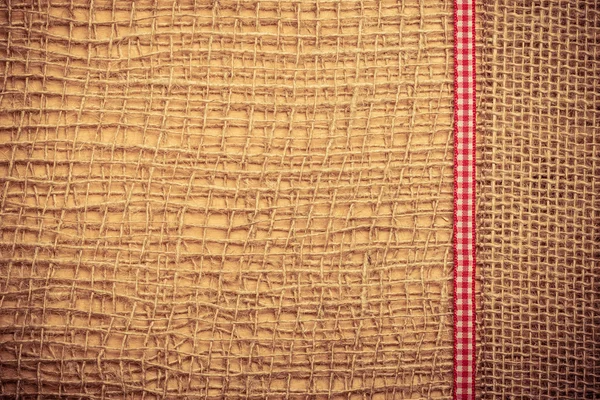 Red ribbon on burlap cloth background — Stock Photo, Image