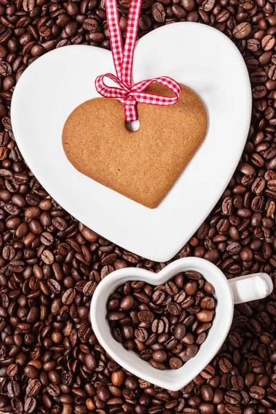 Herzförmige Tasse und Plätzchen auf Kaffeebohnen Hintergrund — Stockfoto