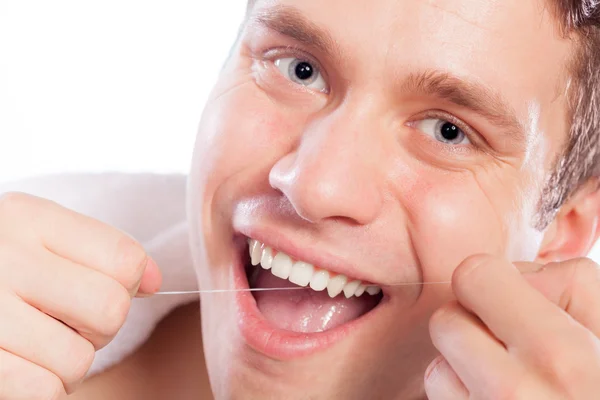Молодий чоловік чистить білі зуби зубною ниткою — стокове фото